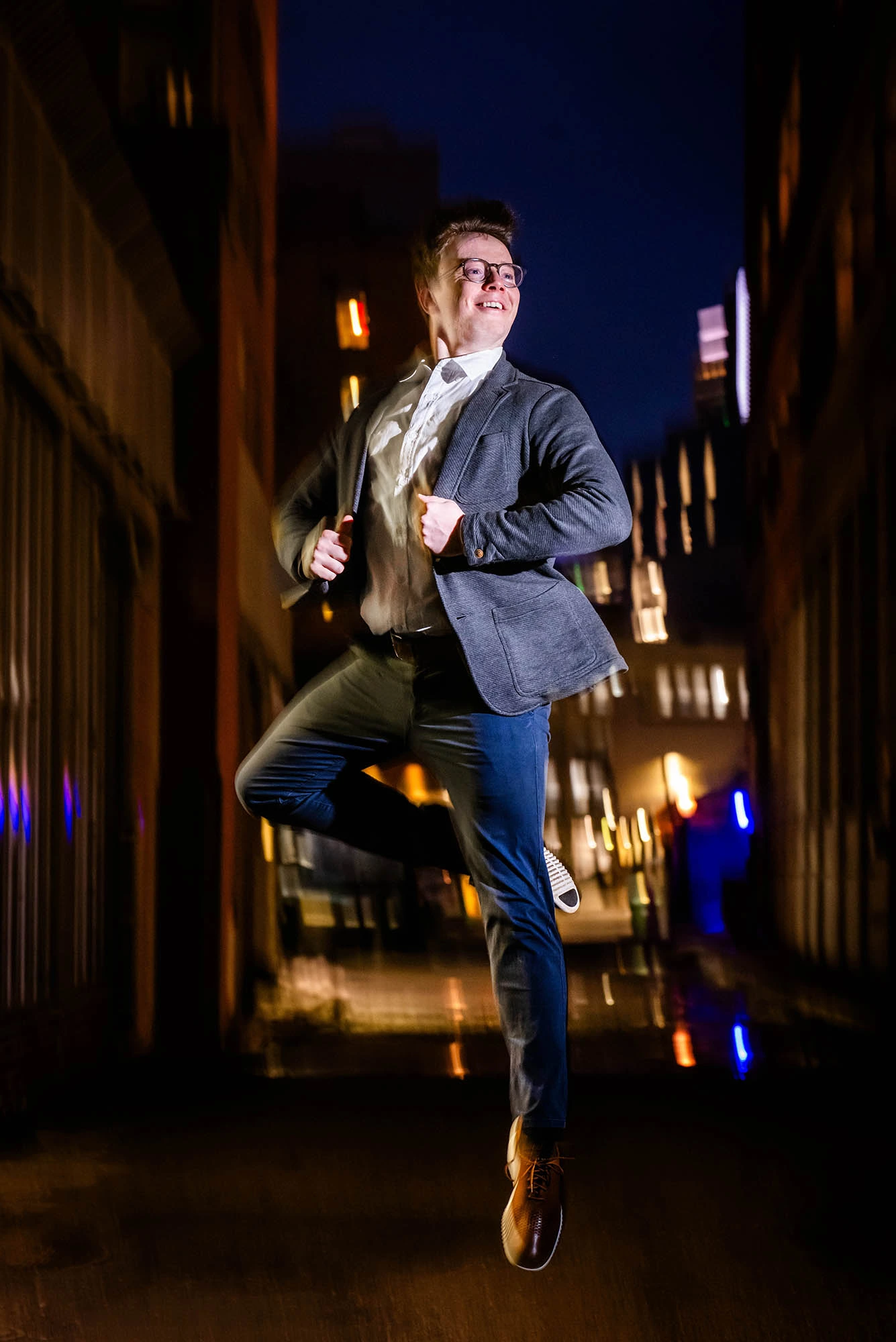 Isaac Akiva smiling and dressed smartly performs a ballet move.