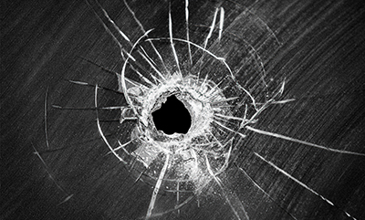 Bullet shot cracked hole on broken window glass