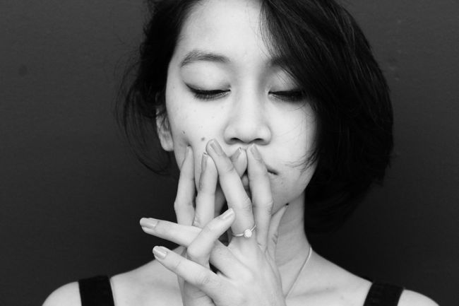 worried Asian American woman looks down at her hands