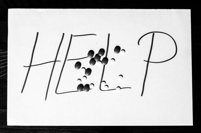 Help sign letters written on paper with strong pain killer pills or tablets addiction or suicidal concept black and white