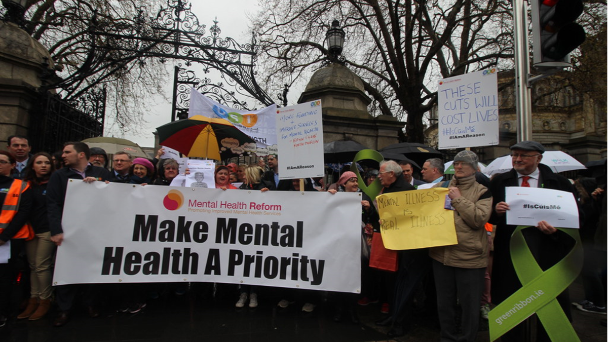 protestors hold sign that says "Make Mental Health a Priority"