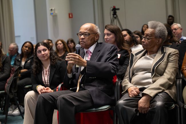 Honored speaker addressing lecture audience next to wife, Katherine